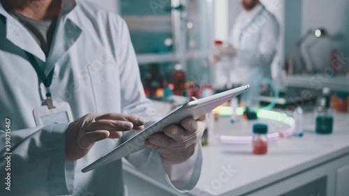 Close-up of lab worker using digital tablet at workspace. Male scientist expert browsing technology device collaborating in medical research laboratory. photo