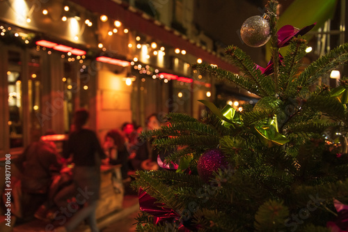 Parisians and tourists enjoy at cafe terrace at evening during winter holidays. Paris, France. Selective focus Christmas tree. © Elena Dijour