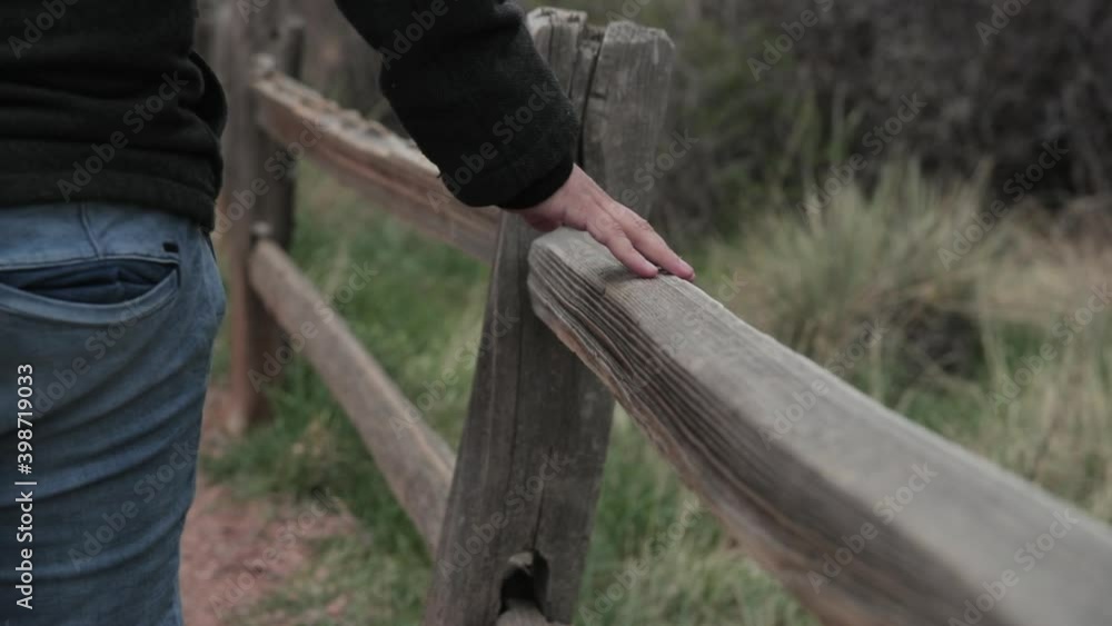 man passing hand through wooden guard rail man passing hand through wooden guard rail