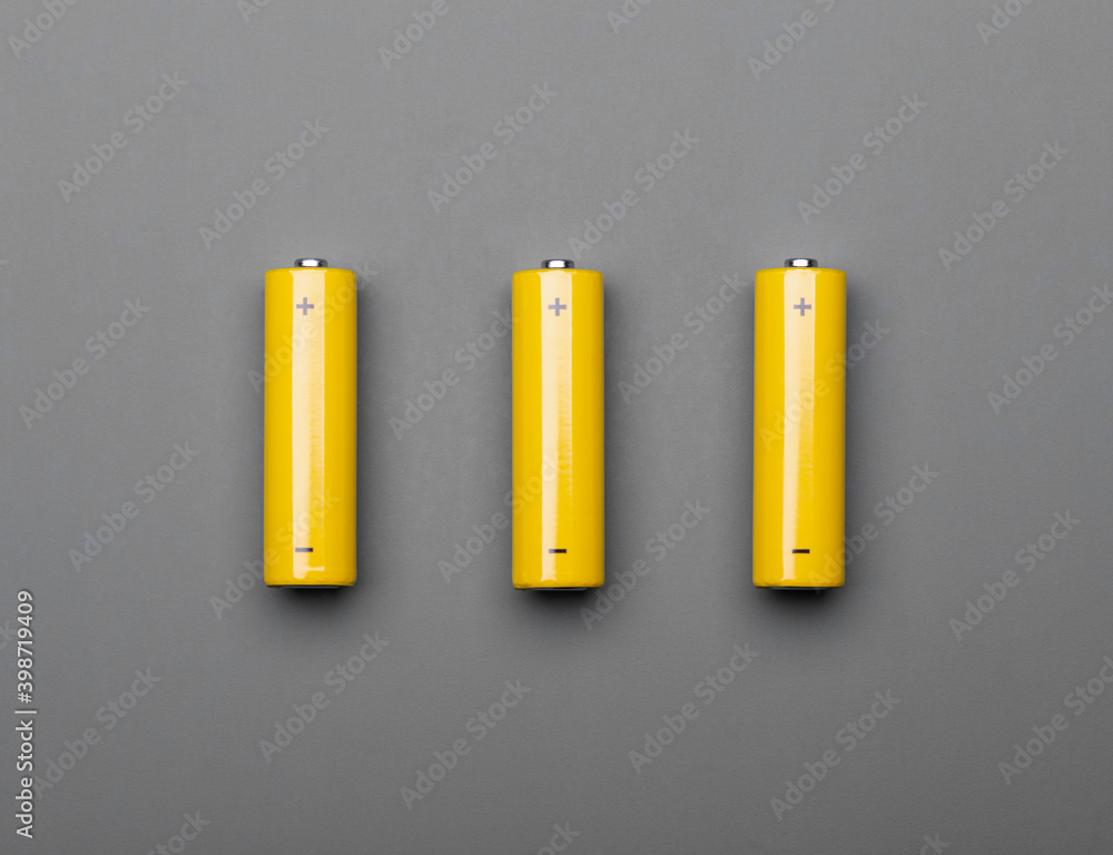 Yellow AA alkaline batteries on gray background colors of the year 2021 concept Yellow AA alkaline batteries on gray background colors of the year 2021 concept
