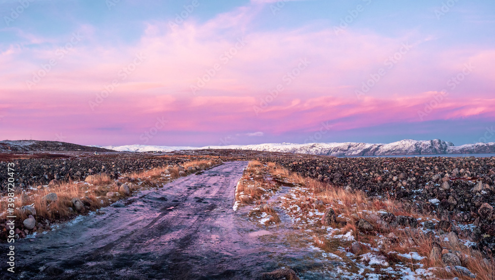 Icy winter road through the tundra in Teriberka. Amazing colorful Arctic landscape