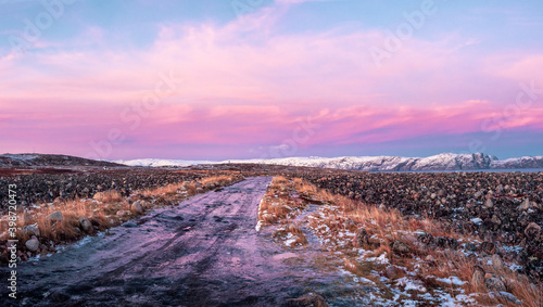 Icy winter road through the tundra in Teriberka. Amazing colorful Arctic landscape