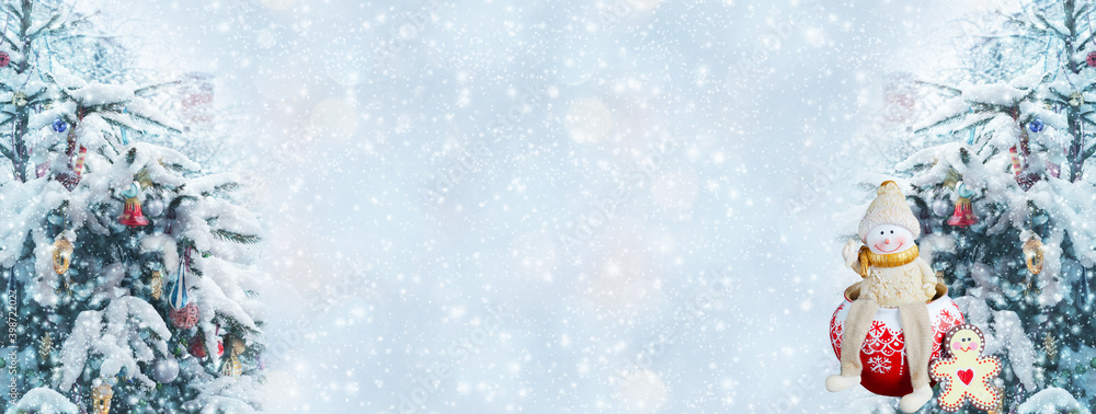 Christmas defocused widescreen background with decorated fir trees and a funny toy snowman. New year's winter art design, banner with bokeh and snow Christmas defocused widescreen background with decorated fir trees and a funny toy snowman. New year's winter art design, banner with bokeh and snow