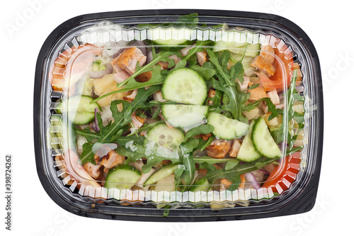 Take away chicken salad in a black plastic box. Studio photo isolated on white background.