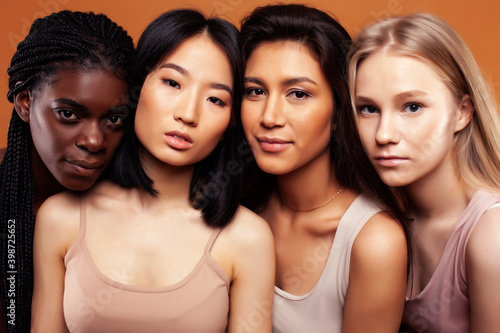 young pretty asian, caucasian, afro woman posing cheerful together on brown background, lifestyle diverse nationality people concept