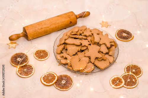 Festive Christmas still life in the kitchen, gingerbread cookie, rolling pin, garland lights, oranges photo