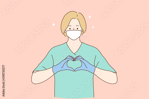 Doctors help and love, safety and care during coronavirus pandemic concept. Woman professional medic or nurse in protective face mask, gloves and green working uniform forming heart with fingers 