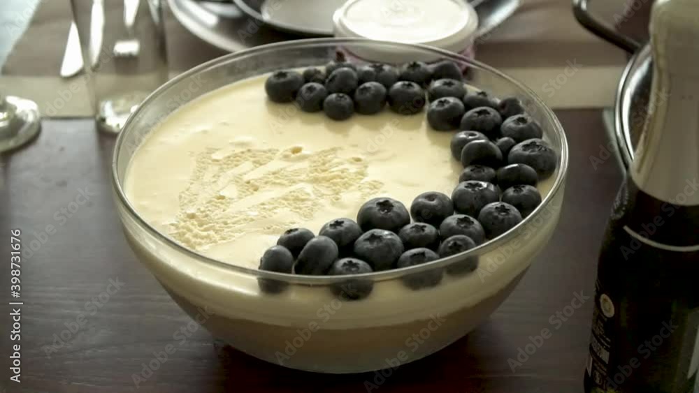 Close up of delicious cheesecake with blueberries on top served with champagne and a sparkling wine bottle in a kitchen. Close up of delicious cheesecake with blueberries on top served with champagne and a sparkling wine bottle in a kitchen.