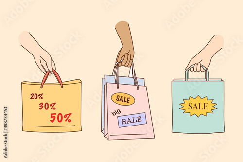 Big sale, shopping, discount in shops concept. People hands holding colorful shopping or gift bags with sale percents and discounts signs and symbols over yellow background illustration 