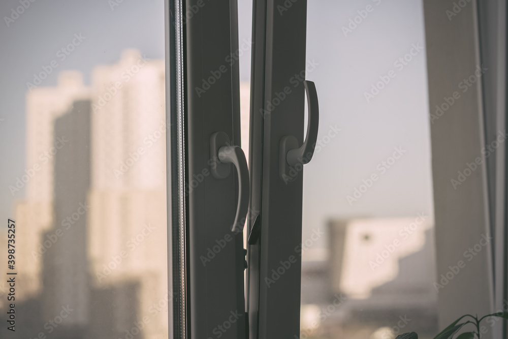 Opening of white plastic window frame with double glazing in room of city house Opening of white plastic window frame with double glazing in room of city house