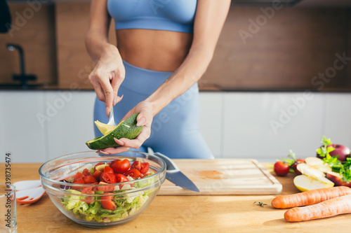 close up picture of pretty fitness girl preparing vegetable and avocado salad in her kitchen, Healthcare concept.
