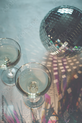 Glass of champagne in a coupe with disco ball and sparkles. New Year party, birthday, girls day or other celebration event