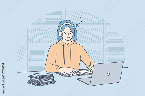 Using gadgets, listening to music during e-learning concept. Smiling teen girl college student with blue hair in headphones watching online webinar or online tutorial on laptop and making notes 