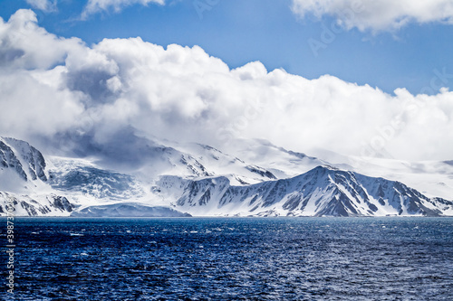 Fotografija Sharp peaks and ridges covered in deep snow and soft clouds