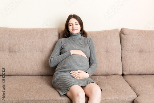 Pregnancy woman in beautiful dress sitting on the home