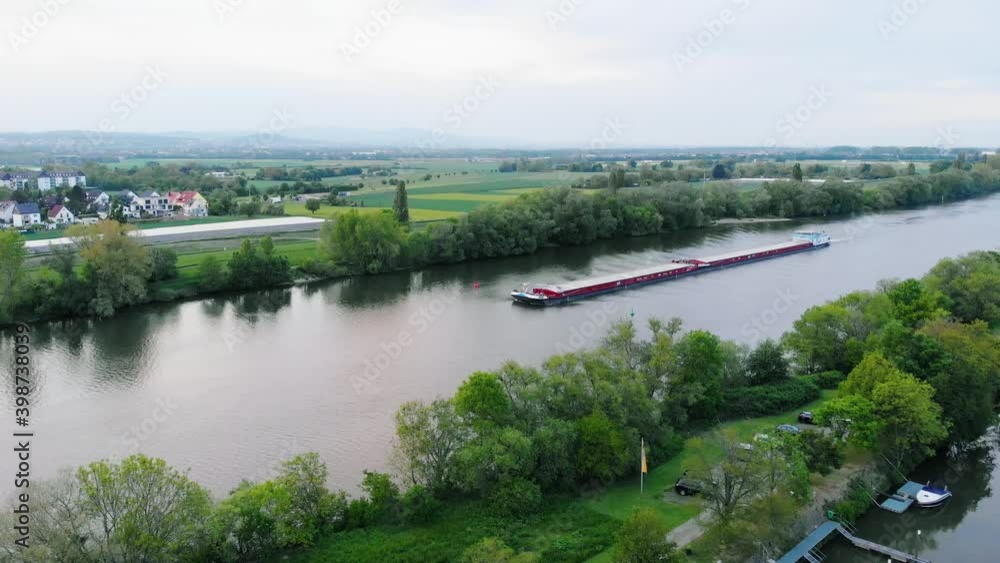 Aerial view of a Inland waterway shipping, freight transport on Main river, in Raunheim village, Germany - static, drone shot Aerial view of a Inland waterway shipping, freight transport on Main river, in Raunheim village, Germany - static, drone shot