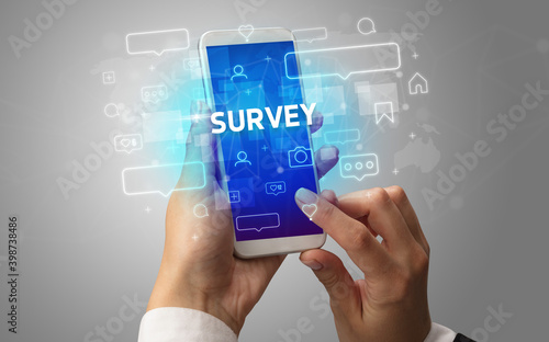 Female hand typing on smartphone with SURVEY inscription, social media concept