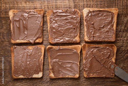 Toast with chocolate-nut paste spread on wooden background top view