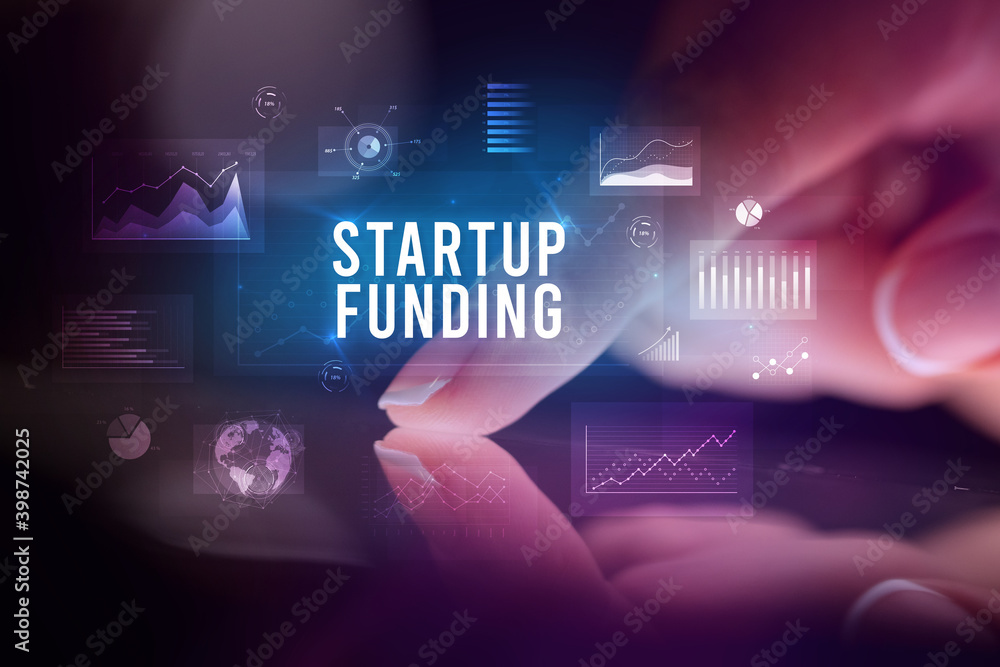 Finger touching tablet with charts and STARTUP FUNDING inscription, business concept Finger touching tablet with charts and STARTUP FUNDING inscription, business concept