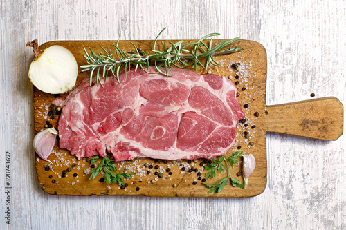 Fresh raw pork neck with spices on wooden board closeup, ingredients for a delicious meat meal photo