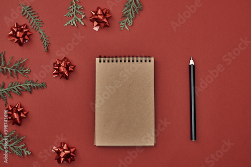 New Year's decor and a notebook in the center on a red background. Christmas decoration. Copy space, flat lay, mock up, top view