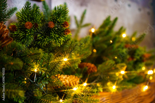 artificial spruce branch with cones and garland bulbs on a wooden shelf.