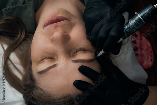 Permanent eyebrow makeup procedure. Eyebrow tattooing, process. The use of tools by a master for permanent eyebrow makeup.