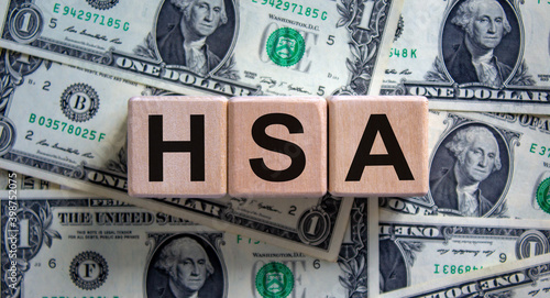 HSA symbol. Wooden cubes with the word 'HSA - Health Savings Account'. Beautiful background from dollar bills. Business and HSA concept. photo