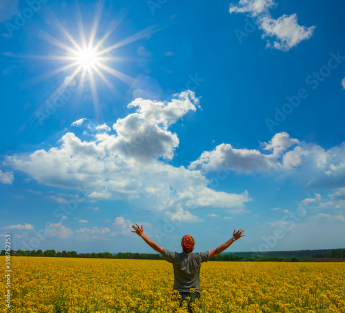 happy man stay among yellow rape field under a sparkle sun
