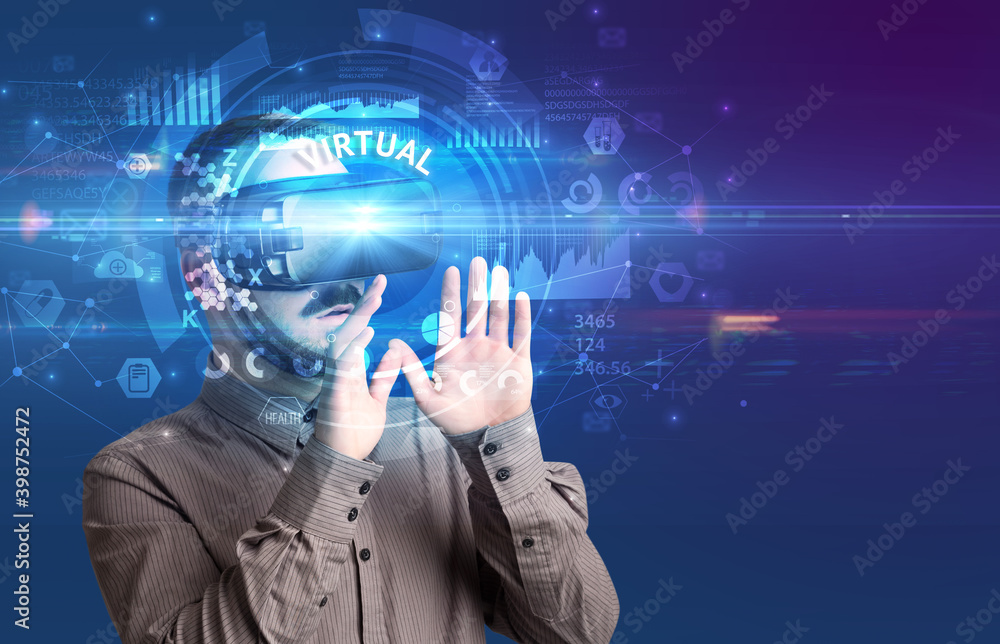 Businessman looking through Virtual Reality glasses with VIRTUAL inscription, innovative technology concept Businessman looking through Virtual Reality glasses with VIRTUAL inscription, innovative technology concept