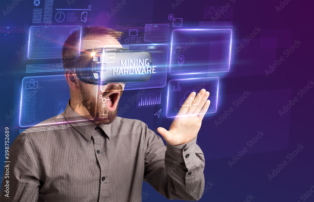 Businessman looking through Virtual Reality glasses with MINING HARDWARE inscription, new technology concept Businessman looking through Virtual Reality glasses with MINING HARDWARE inscription, new technology concept
