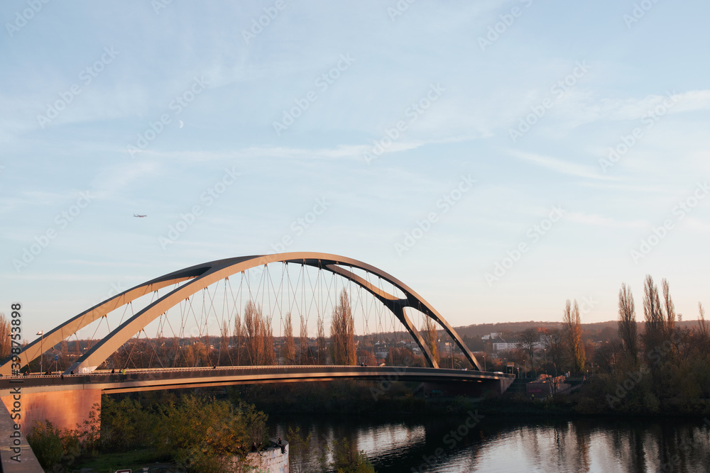 Naklejka premium Frankfurt Osthafenbrücke, blue sky and a plane in the background.