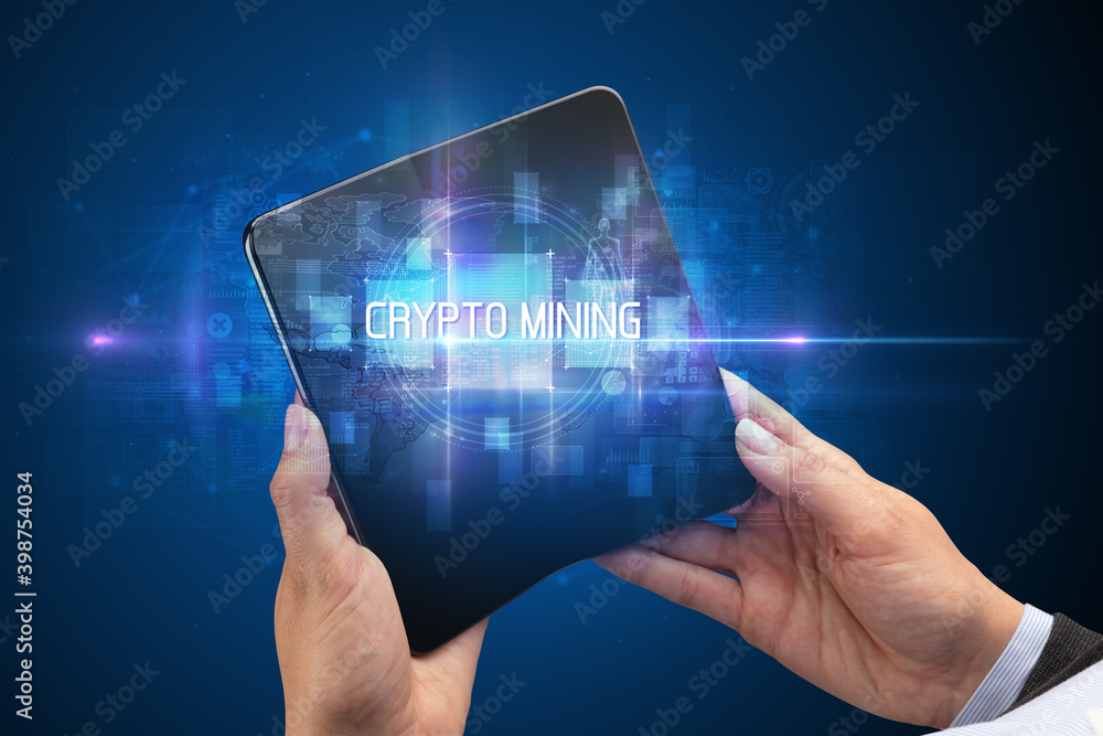 Businessman holding a foldable smartphone with CRYPTO MINING inscription, new technology concept Businessman holding a foldable smartphone with CRYPTO MINING inscription, new technology concept