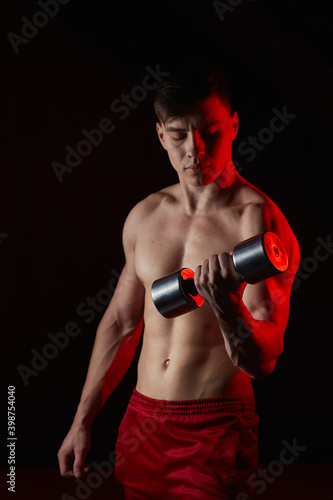 Sporty young man training with dumbbells against dark background © Ryzhkov Oleksandr