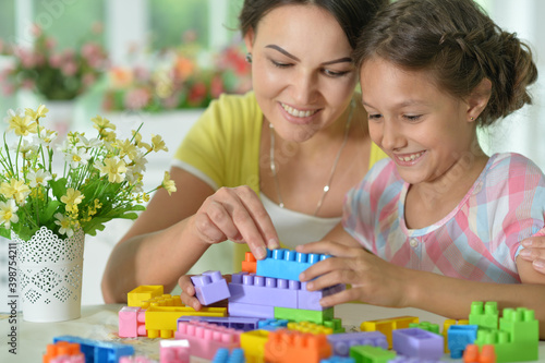 Daughter and mother playing with colorful plastic blocks at home