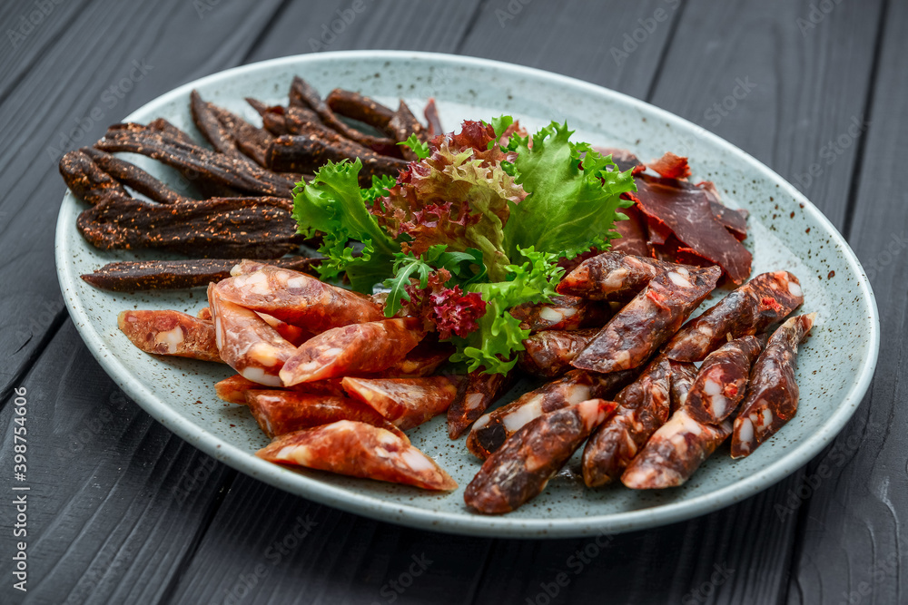 Traditional dry-cured sausage and jerky on a plate Traditional dry-cured sausage and jerky on a plate