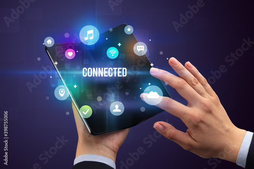 Businessman holding a foldable smartphone with CONNECTED inscription, social media concept