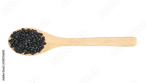 Black beluga lentils pile with wooden spoon isolated on white background, top view