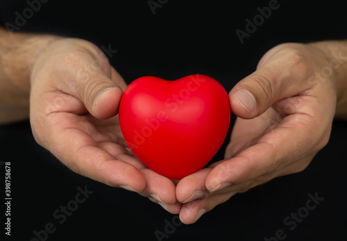 Man holging red heart on dark background. People  relationship  health and love concept