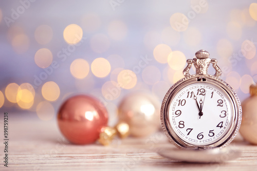 Pocket watch and festive decor on table against blurred lights, space for text. New Year countdown