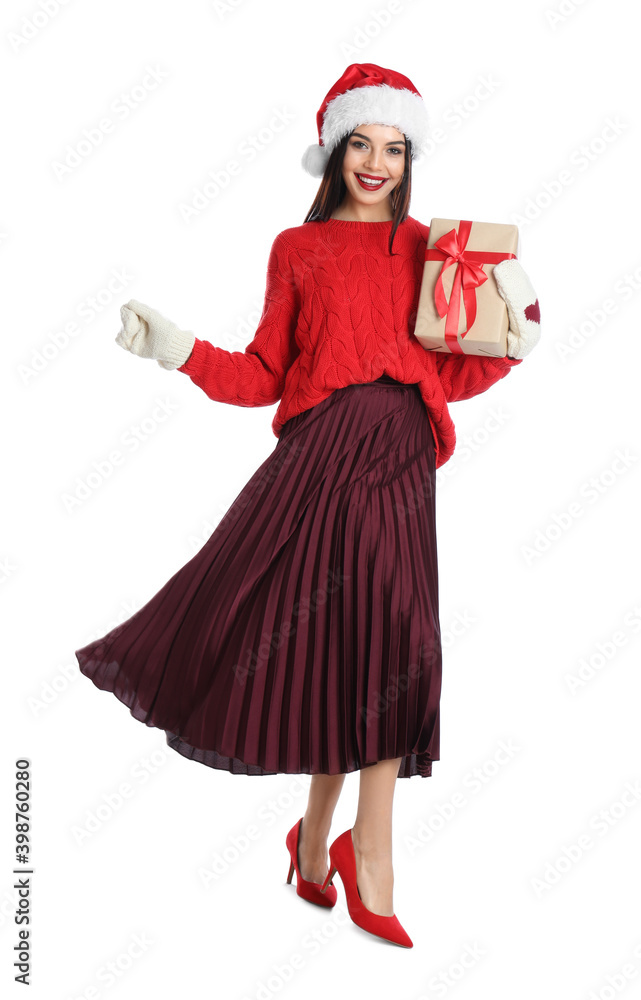 Woman in Santa hat, knitted mittens and red sweater holding Christmas gift on white background