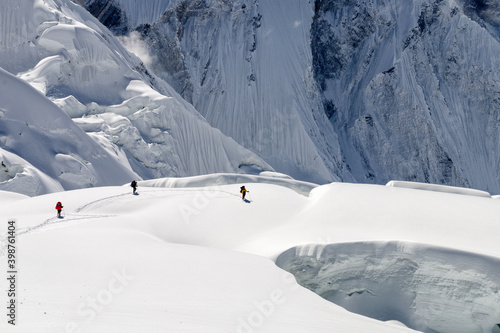Mountain climbers go around glacier crack on the background of Tengri Tau Range. Central Tian Shan, Kazakhstan - Kyrgyzstan - China.