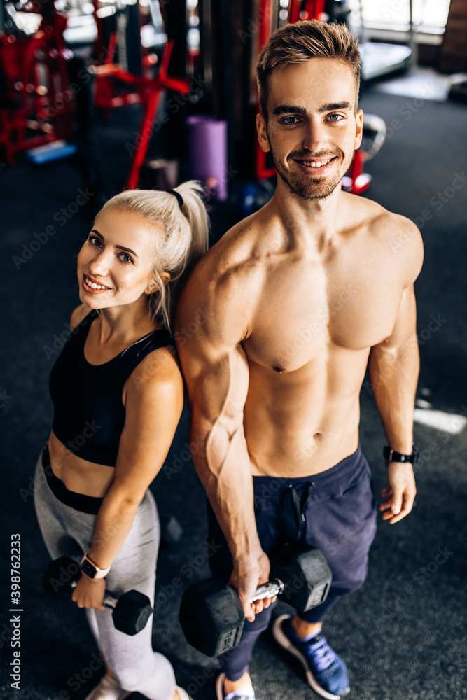 sportive young couple, woman and muscular man, in sportswear, in the gym sportive young couple, woman and muscular man, in sportswear, in the gym