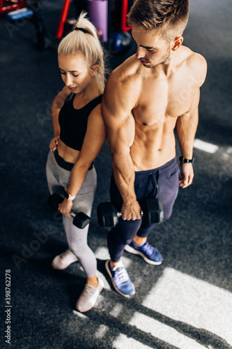 sportive young couple, woman and muscular man, in sportswear, in the gym