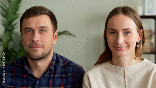 Portrait of a young couple sitting on a sofa. Couple looking at the camera