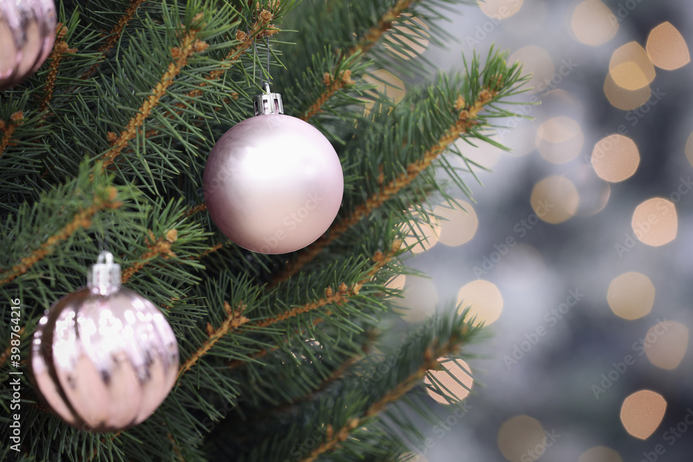 Shiny lilac balls hanging on Christmas tree against festive lights