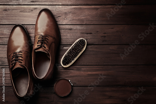 Flat lay composition with shoe care accessories and footwear on wooden background. Space for text