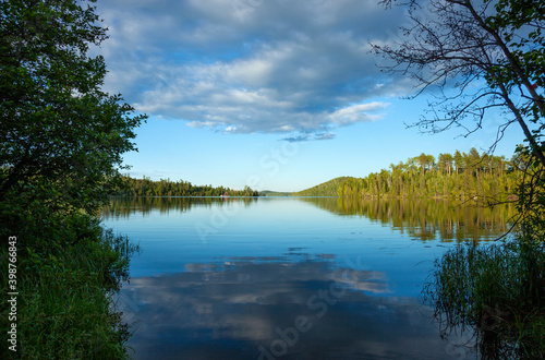 Fototapeta Naklejka Na Ścianę i Meble -  Calm blue northern Minnesota lake and tree line on a sunny evening