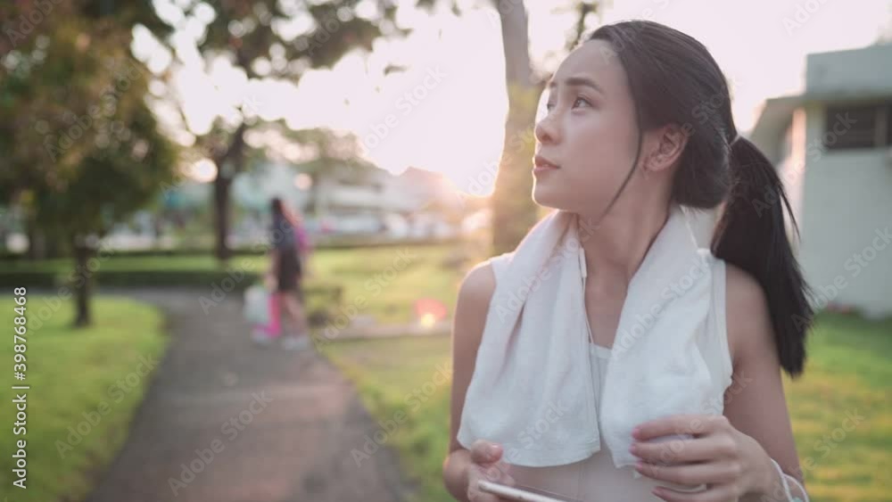 Asian young woman walking at the park after workout, life fitness wellness, self motivation, life insurance plan, healthy lifestyle, with sunset light behind, positive attitude happiness carefree