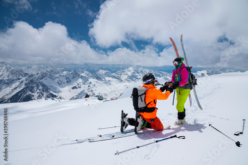 A man athlete skier freerider makes a proposal to marry his woman skier high in the mountains in winter. against the backdrop of snow-capped peaks. Wedding proposal in extreme conditions